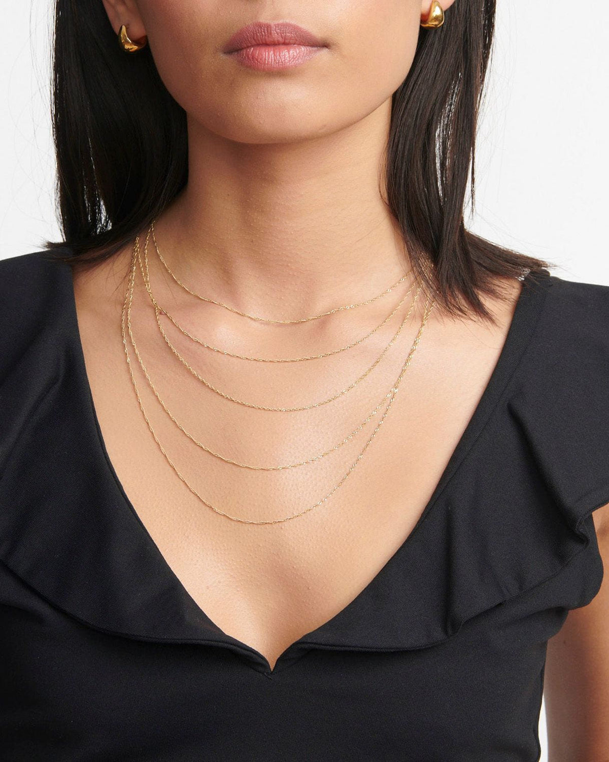 1.2mm Singapore Chains layered at several lengths over a black ruffled top.