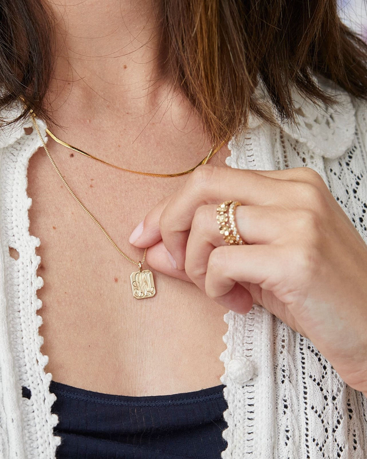 Fingers holding a tablet pendant on the 1mm Singapore Foxtail Chain over a white cardigan.