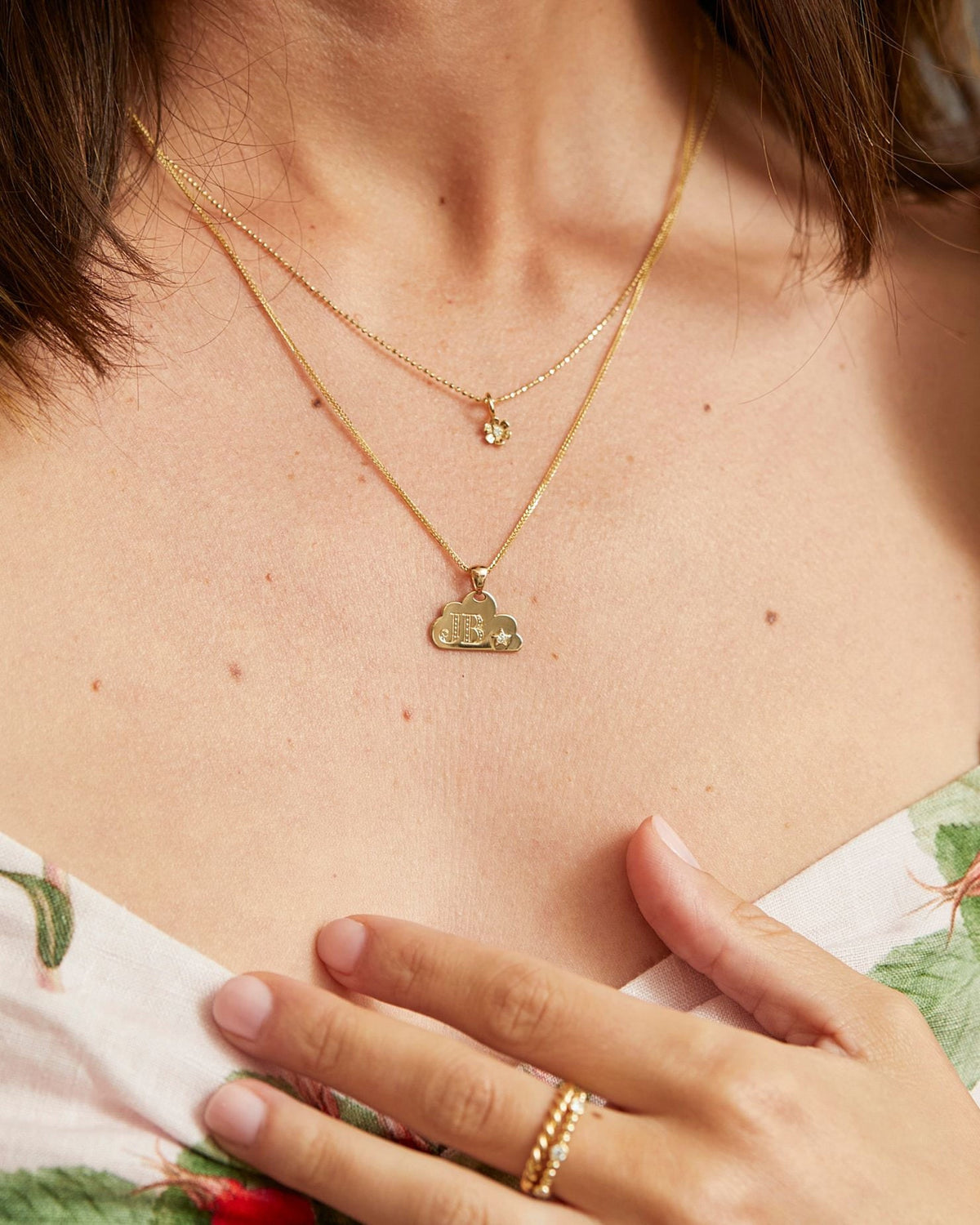 1mm Singapore Foxtail Chain with a charm, hand at the chest of a floral dress.