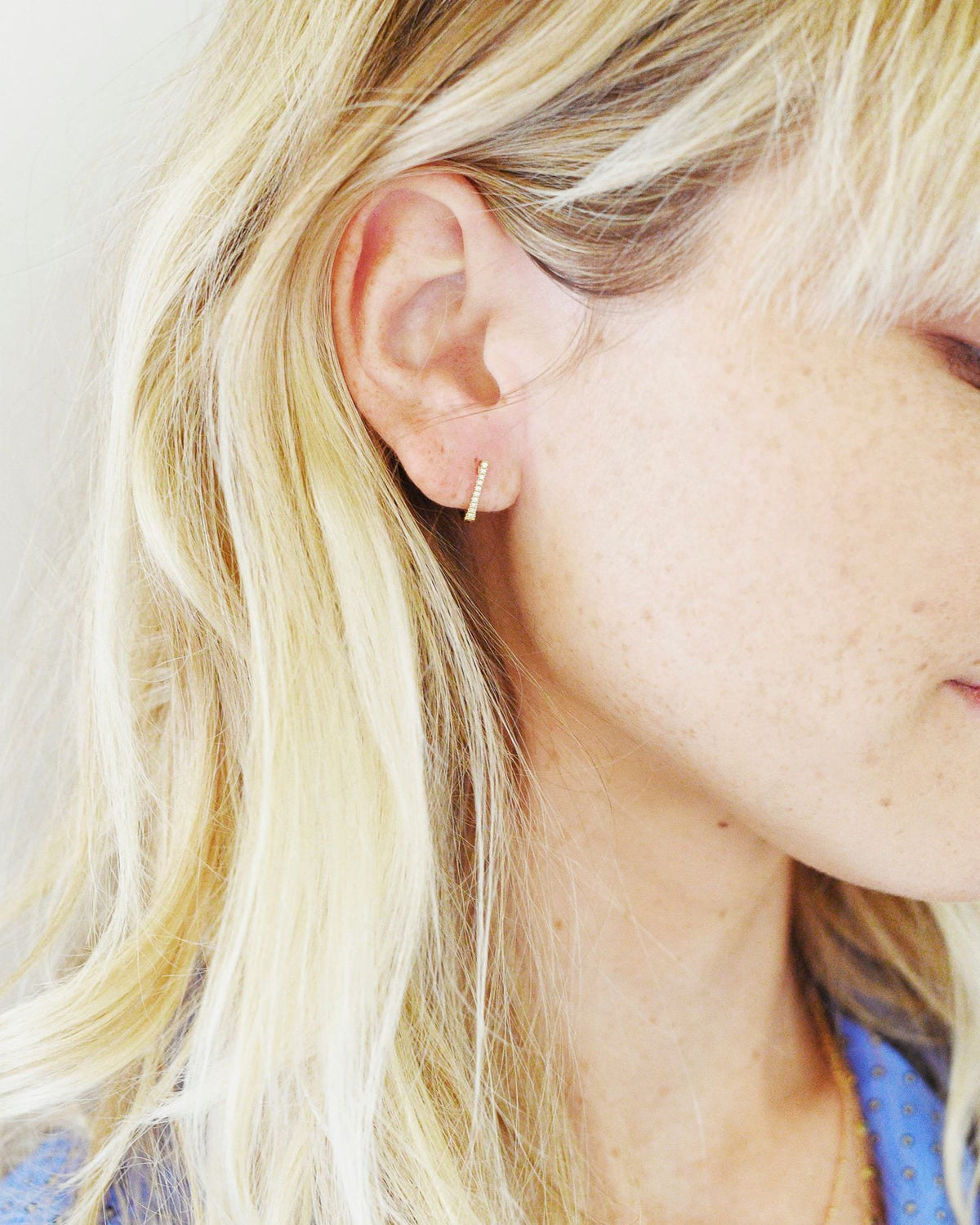 Pave Diamond Huggie on the ear of a blonde model with bangs, her face turned down.