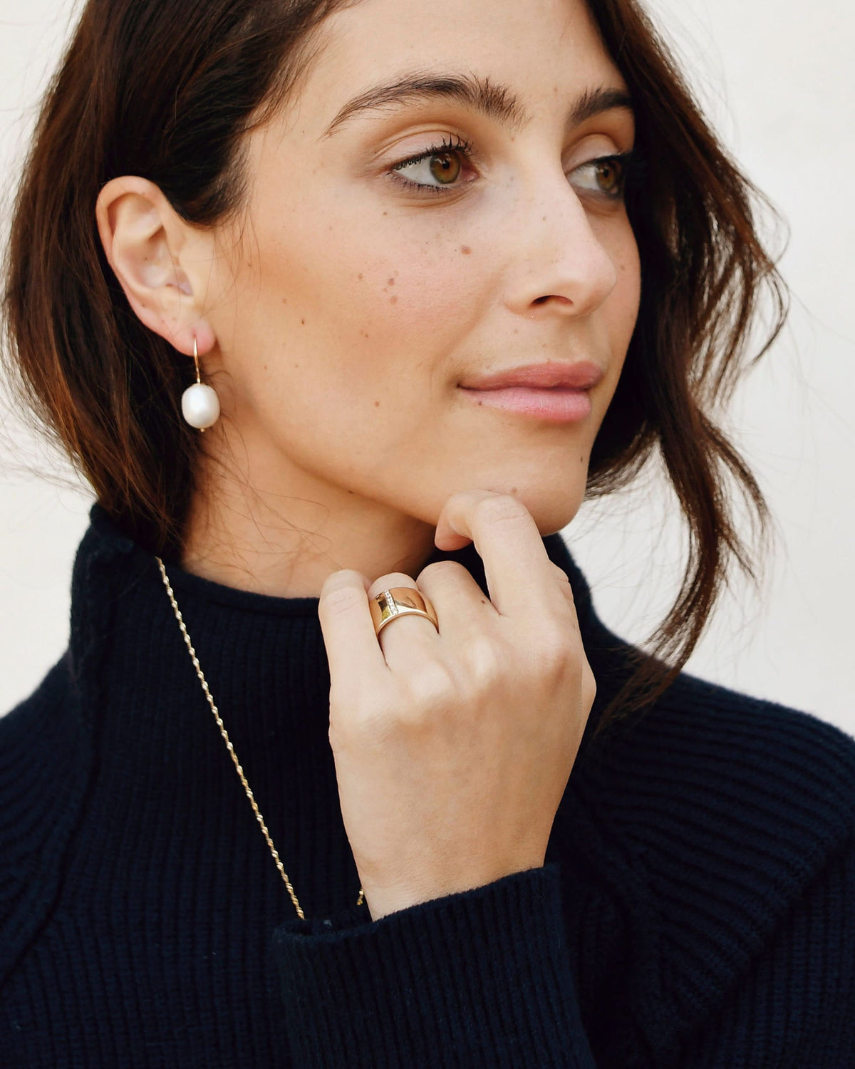 Baroque Pearl Swing Hoop on a model with a short bob and a navy turtleneck, hand at her chin.
