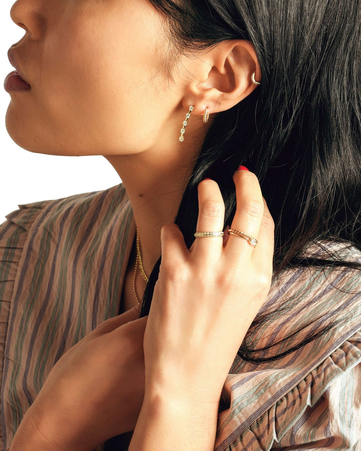 Twisted Petite Hoop beside a diamond drop on a model with long black hair, her hand in her hair.