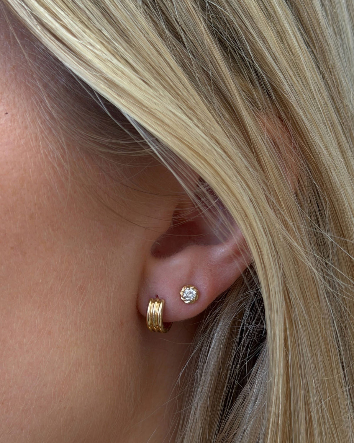 Diamond Twine Stud on the ear of a model with straight blonde hair, worn beside a ribbed gold huggie.