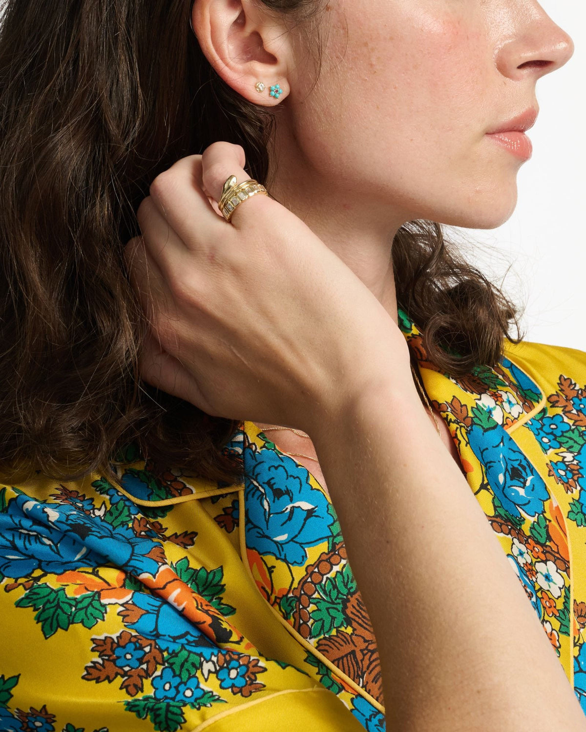 Diamond Twine Stud beside a turquoise flower stud on a model in a yellow floral shirt, hand at her neck.