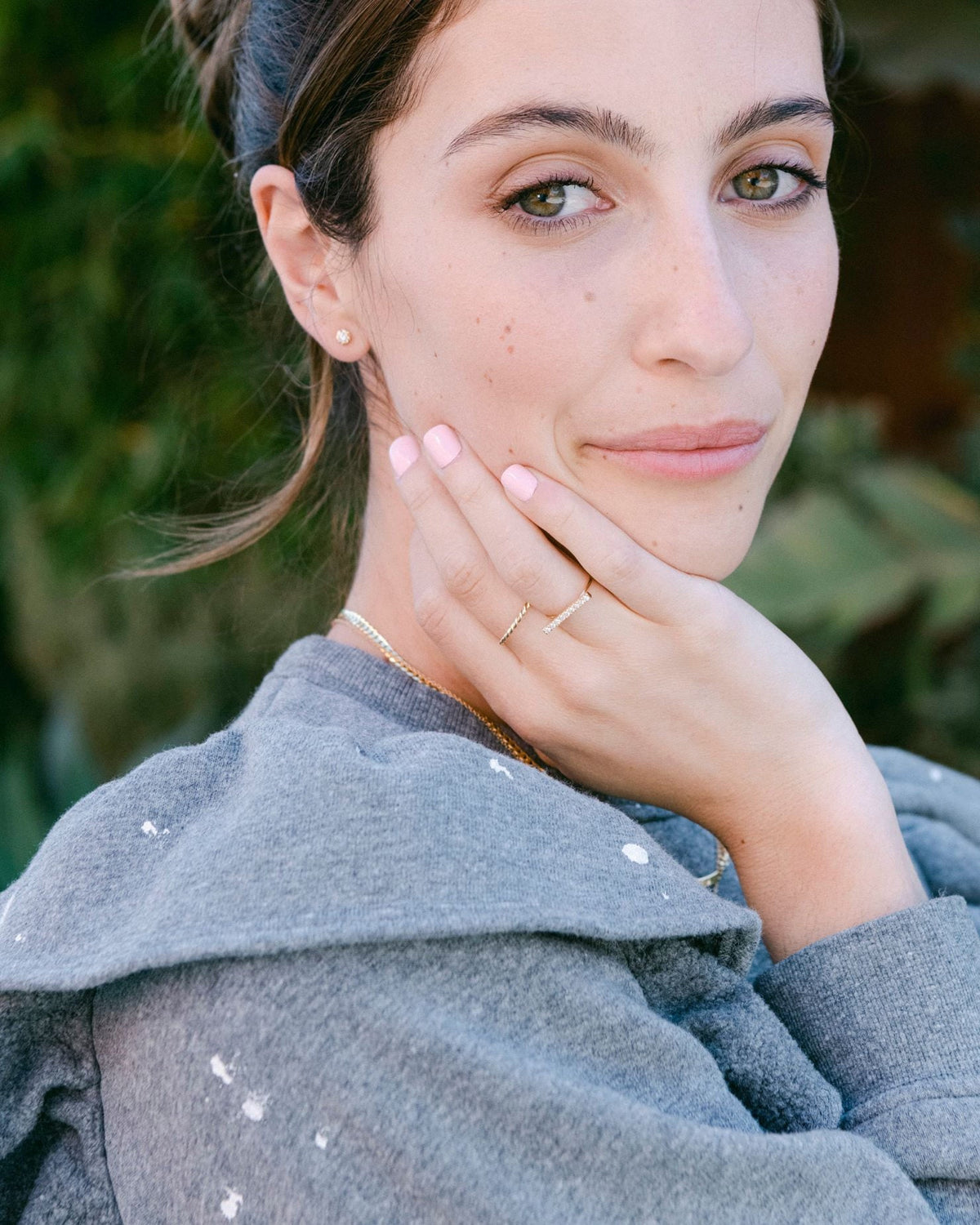 Diamond Twine Stud on a model with her hair pulled back, hand on her cheek, outdoors in a grey sweatshirt.
