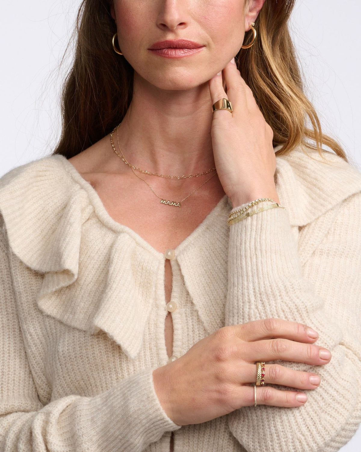 Junior Helium Hoops on a model in a cream ruffle-collar cardigan, her hand at her neck.