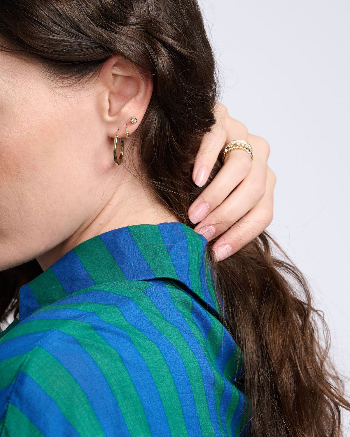 Diamond Hex Stud and gold huggie on a model in a green and blue striped shirt, her hand in her hair.