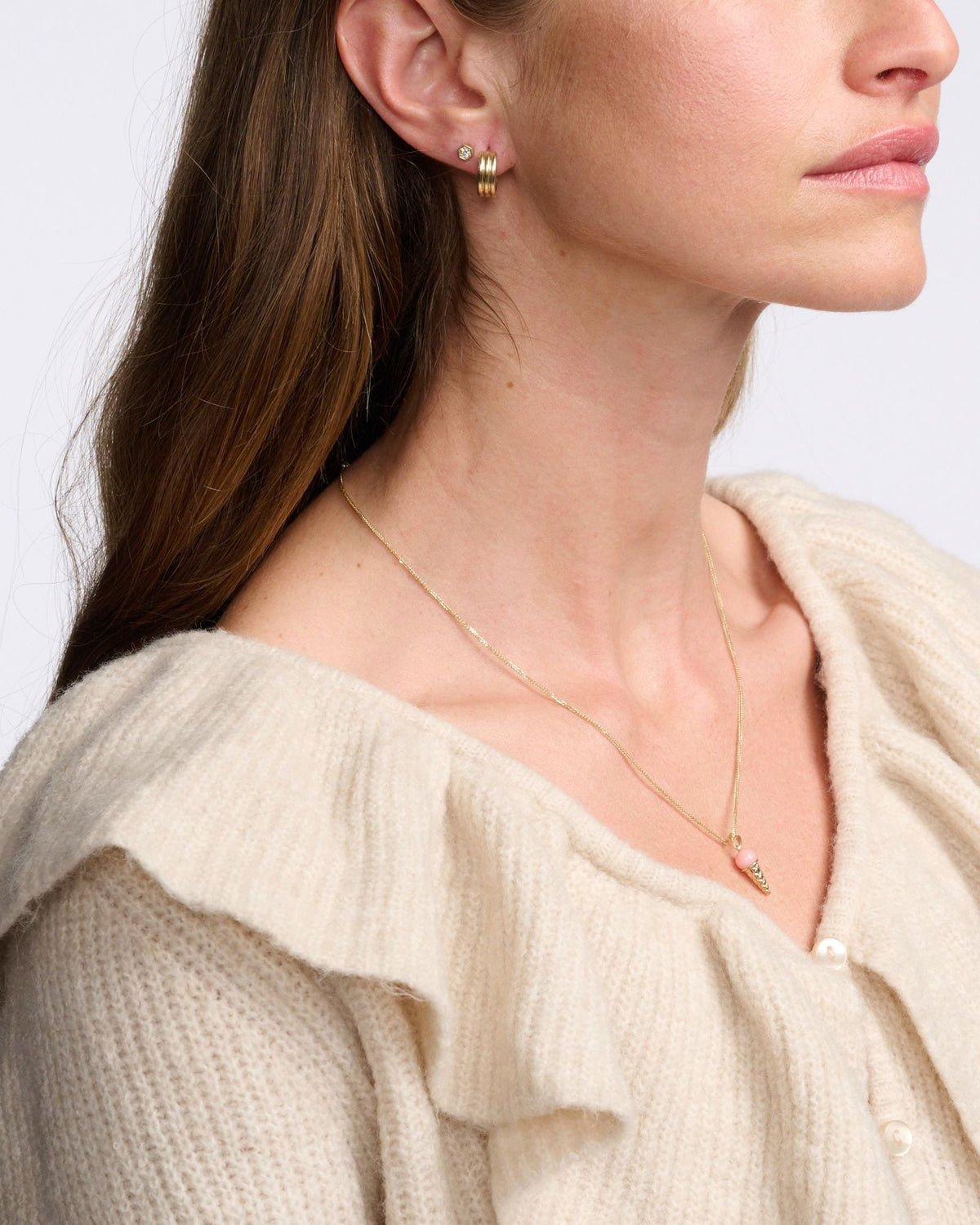 Diamond Hex Stud beside a ribbed gold huggie on a model in a cream ruffle-collar cardigan.