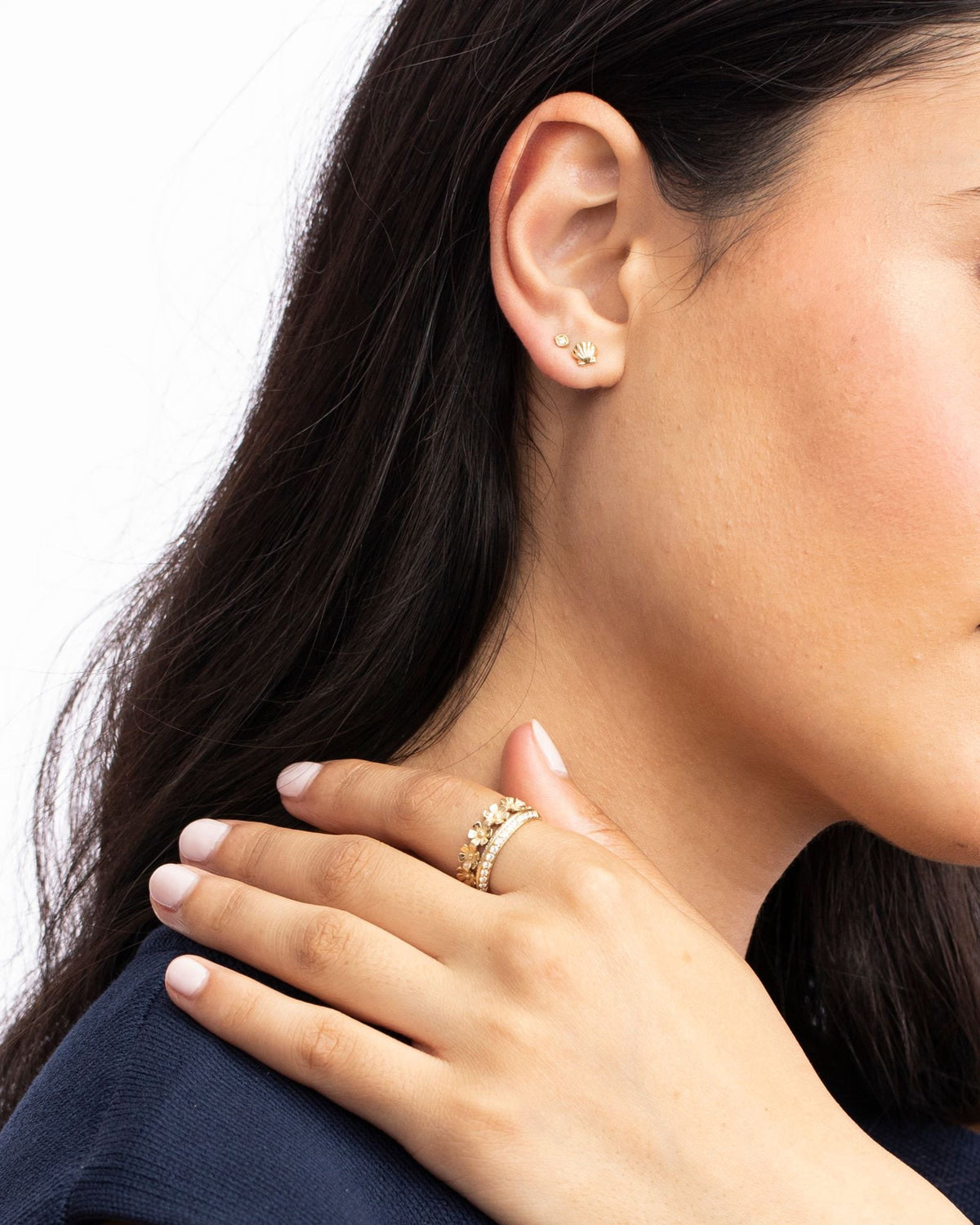 Close-up of a Petite Scallop Shell Stud on the ear, hand at the shoulder.