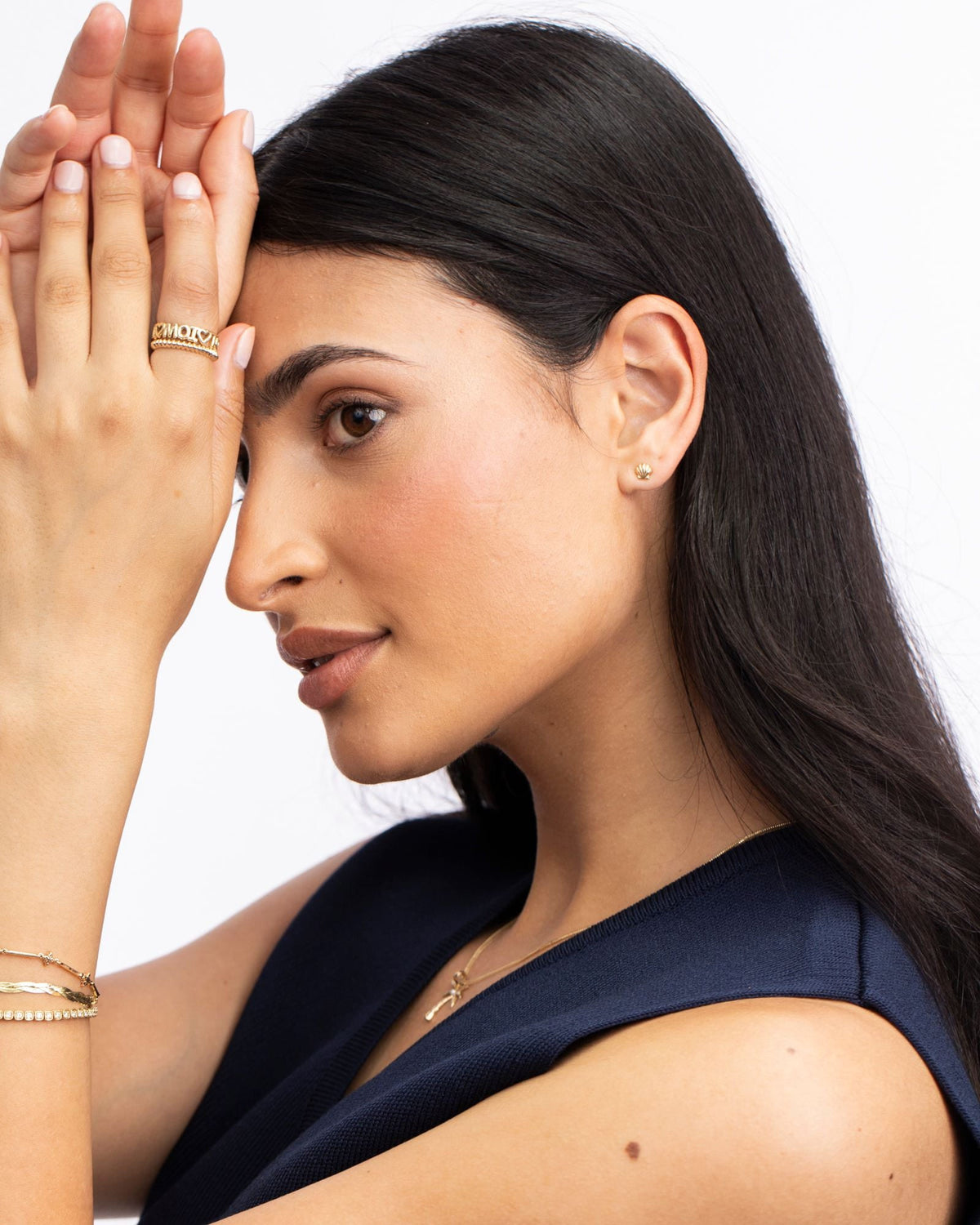 Petite Scallop Shell Stud on the ear with hands raised, navy vest.