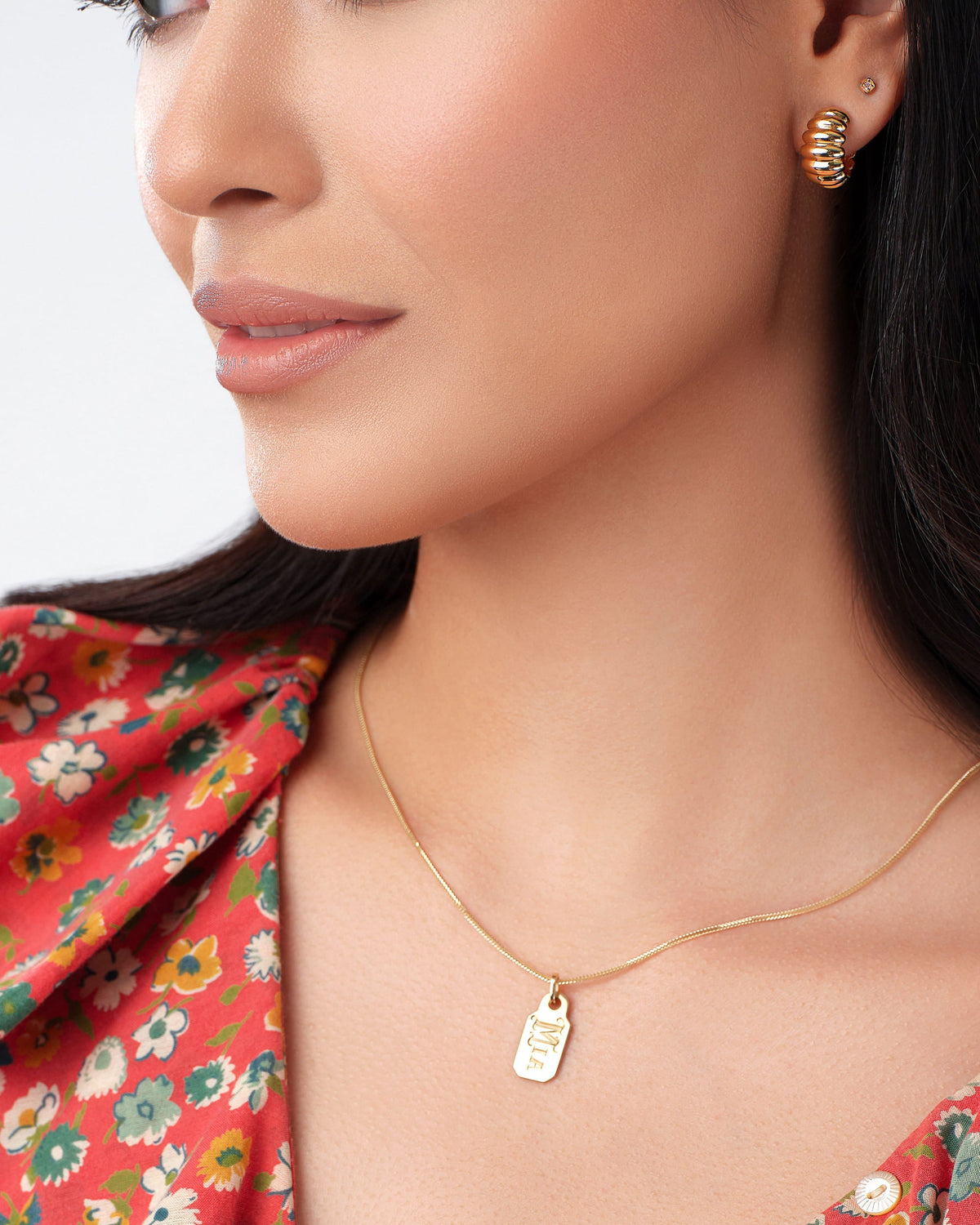 Lady Finger Helium Hoops worn with a red floral top and tag pendant.