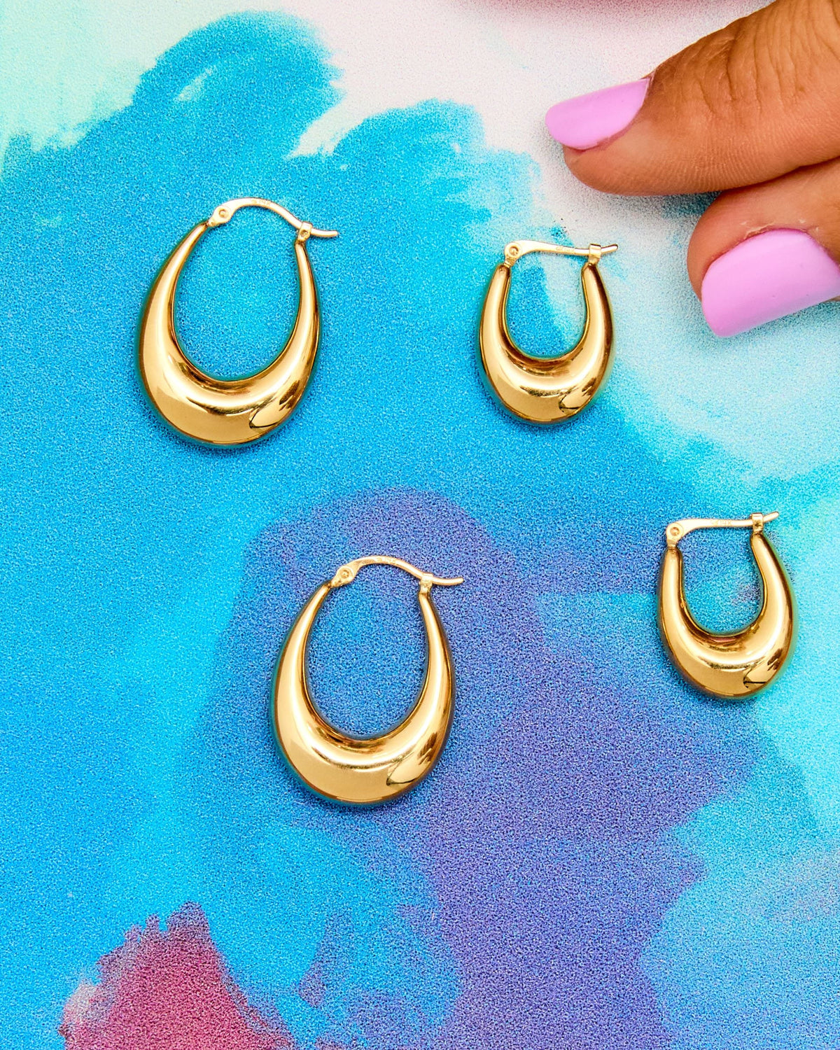 Helium Teardrop Hoops in two sizes on a painted blue background.