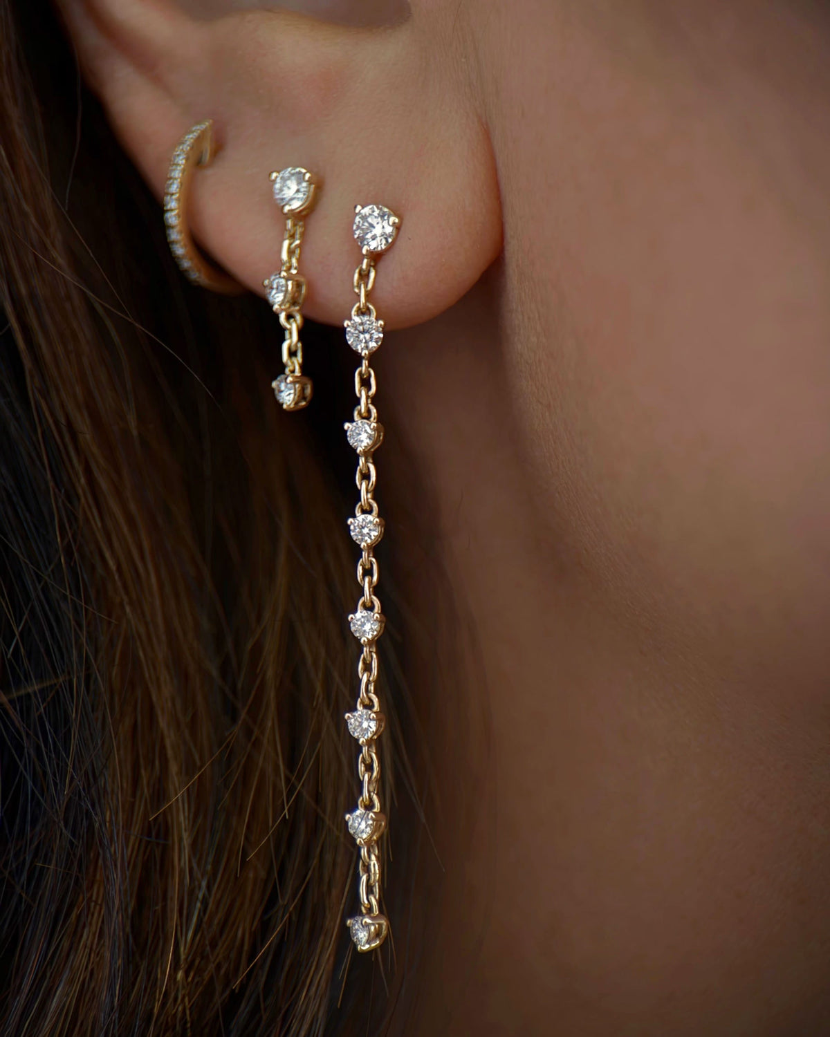 Grande Diamond Cascade Earring on the ear against dark hair, with the shorter cascade.