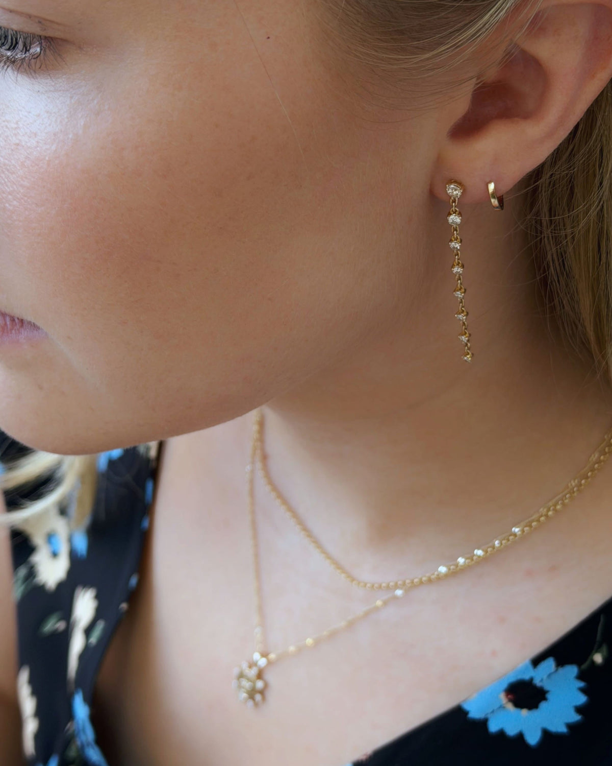 Grande Diamond Cascade Earring worn with layered necklaces and a floral top.