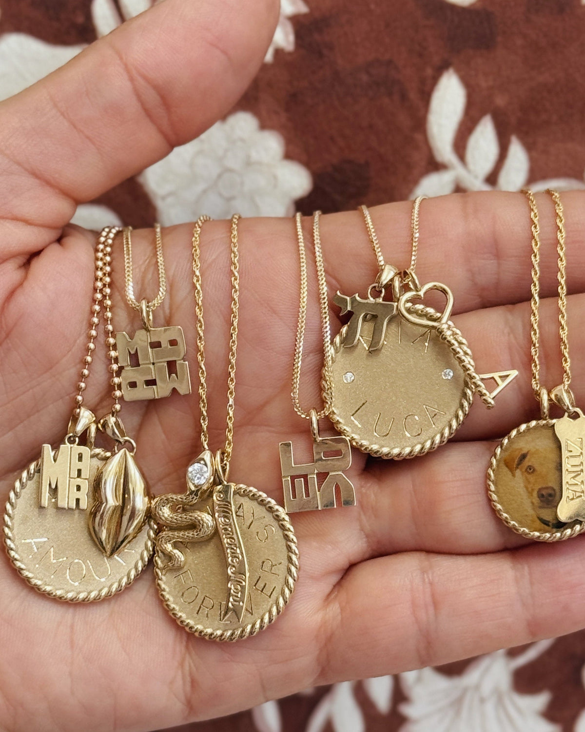 hand engraved personalized charms stacked on assorted gold chains in hand