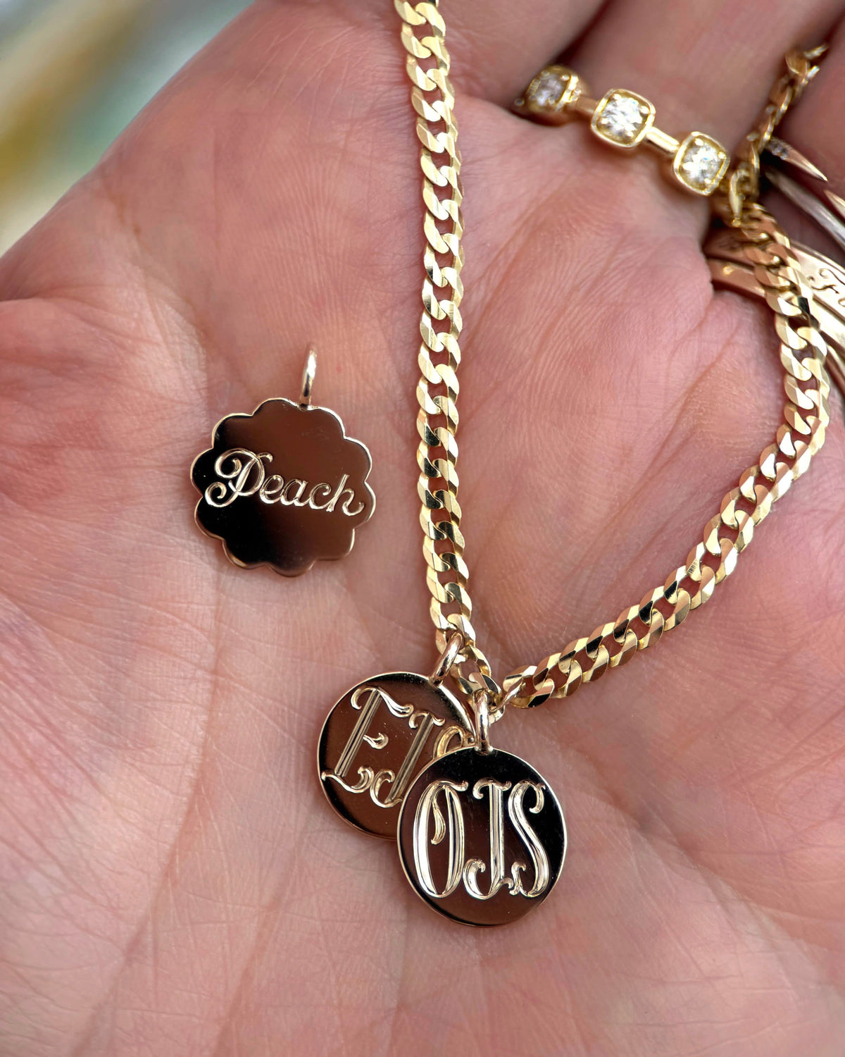 Engraved gold medallions and a curb chain resting in an open palm, showing their size.