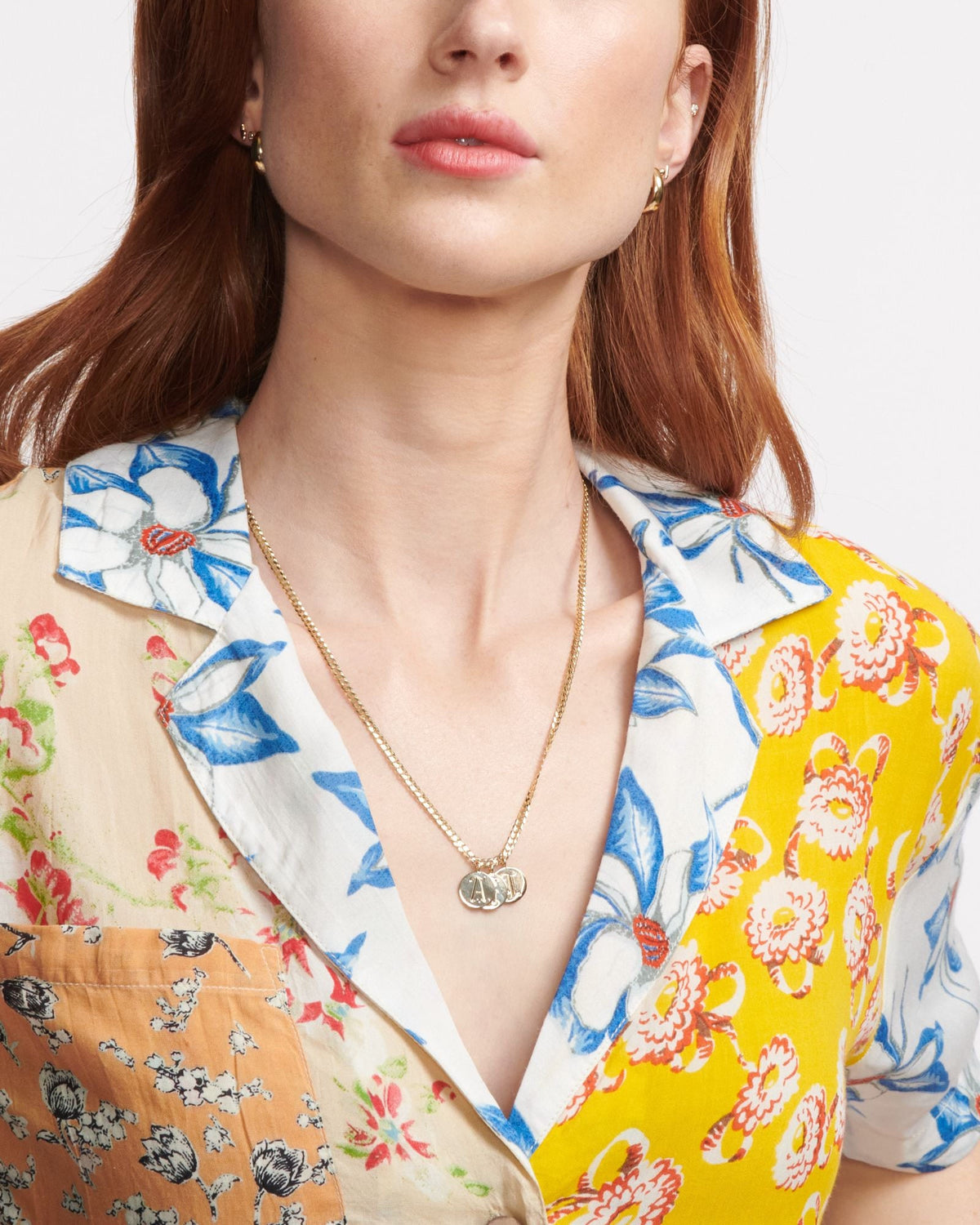 Medallion Signet Necklace on a model in a floral mixed-print blouse, the engraved pendant resting at her open collar.