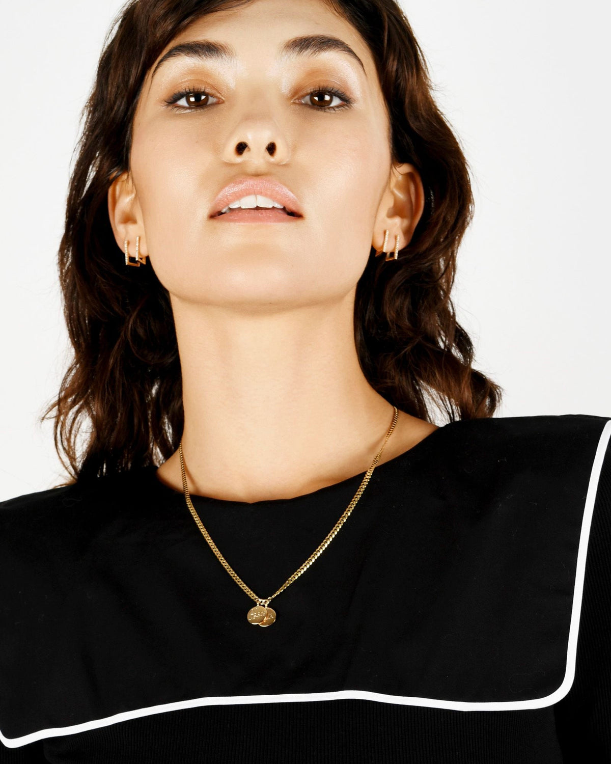 Medallion Signet Necklace on a model in a black ruffle-trim dress, the pendant centered on a curb chain at her collarbone.
