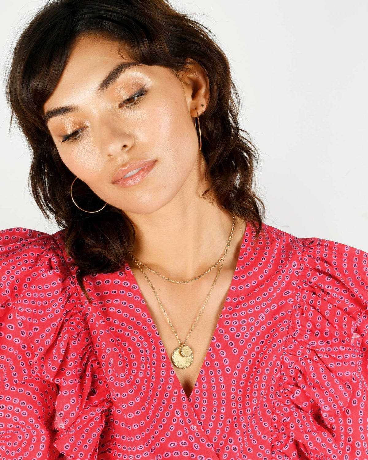 Imperial Disc Pendant on a thin chain, centered on a model's chest against a pink printed ruffle blouse.