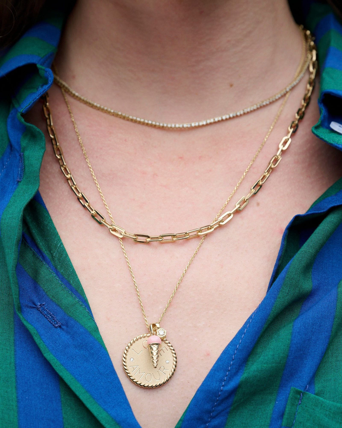 Classic Link Necklace layered between a diamond tennis necklace and a coin pendant on a model in a striped shirt.
