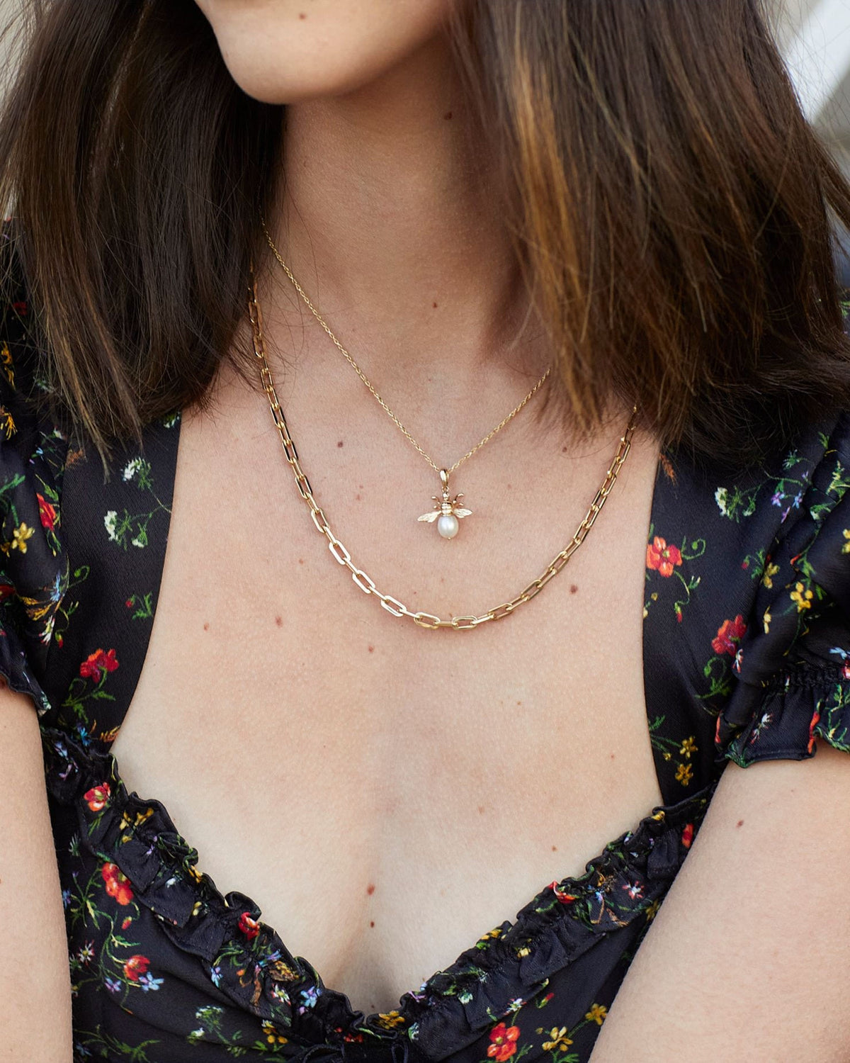 Classic Link Necklace layered under a pearl bee pendant on a model in a dark floral dress.