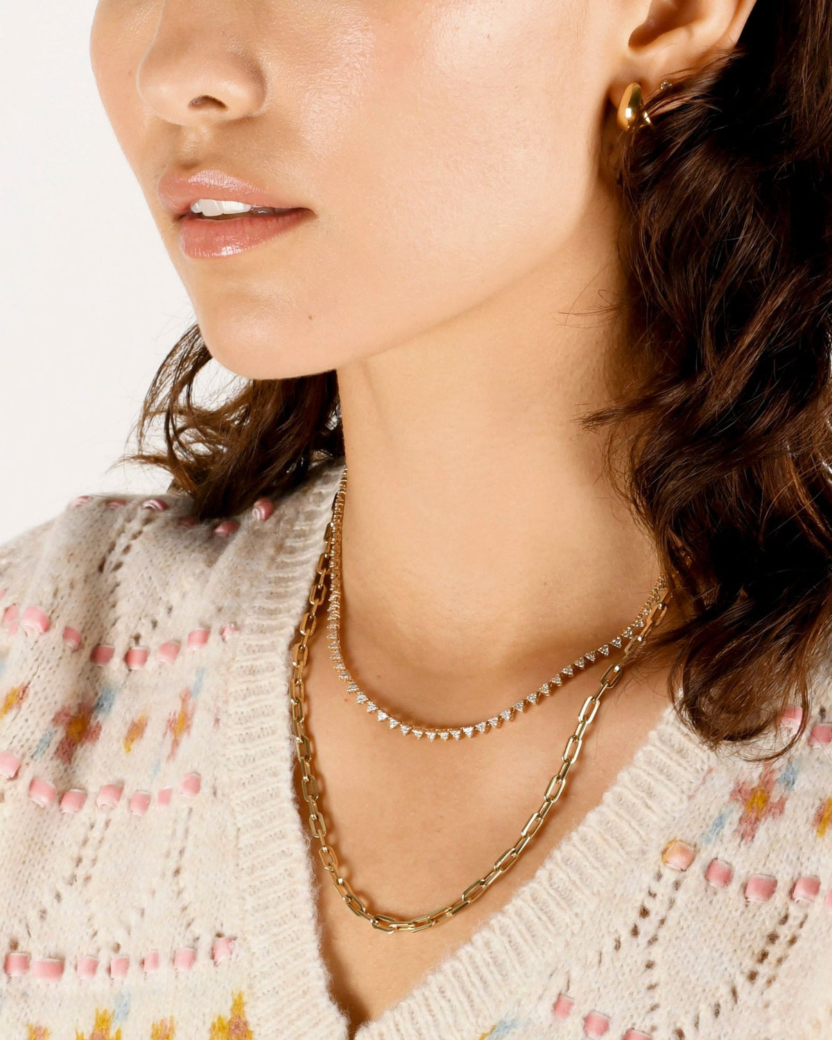 Classic Link Necklace layered under a triangle diamond necklace on a model in a cream pointelle cardigan.