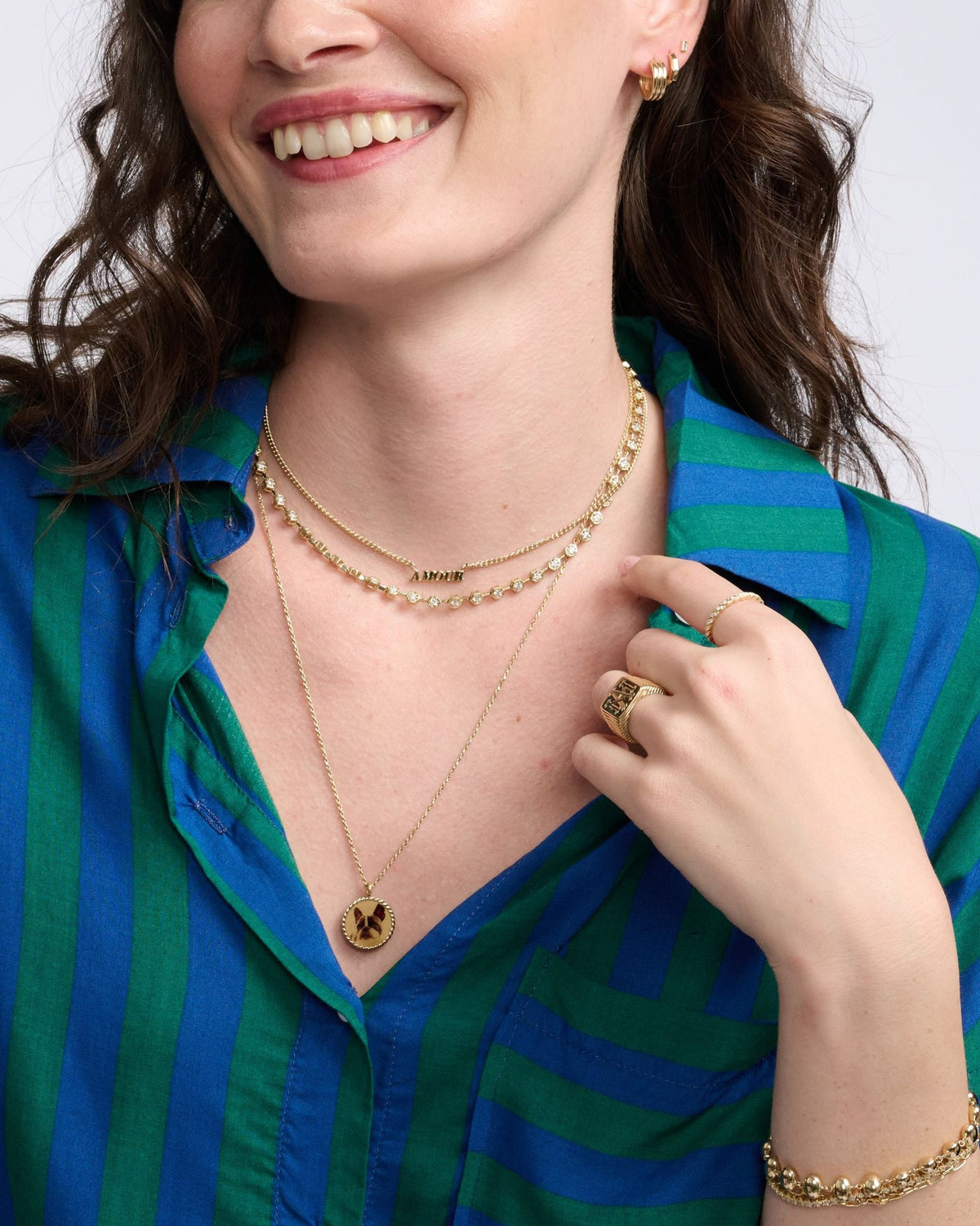 Imperial Portrait Pendant on a smiling model in a green and blue striped shirt, her hand at her collar.