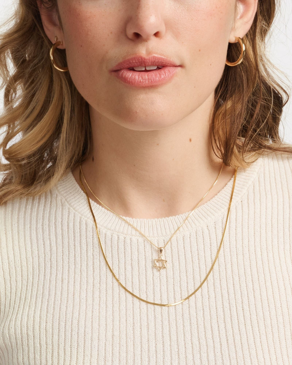 Star of David Talisman Charm layered with a herringbone chain over a cream knit tee.
