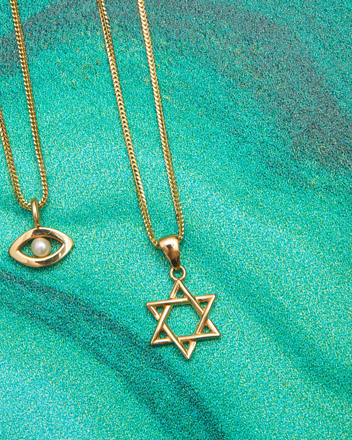 Star of David and Evil Eye Talisman Charms on a malachite background.