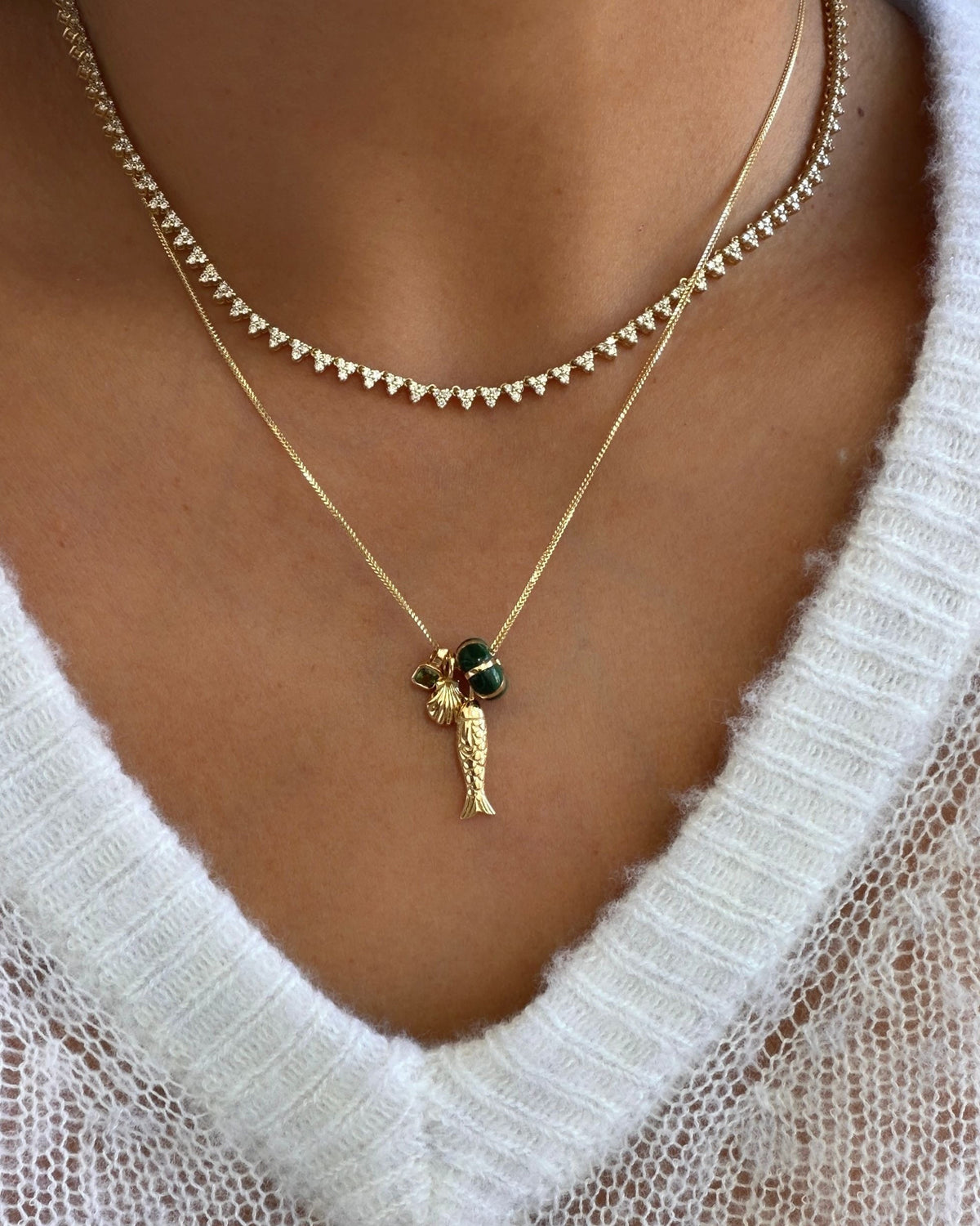 Poisson Pendant layered under a diamond tennis necklace over a white sweater.