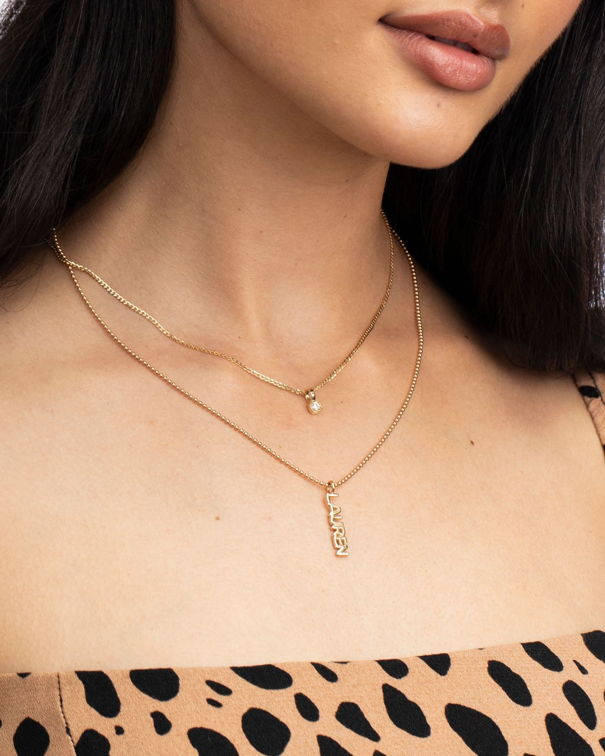 Grande Diamond Ace Pendant layered with a name necklace over a leopard print top.