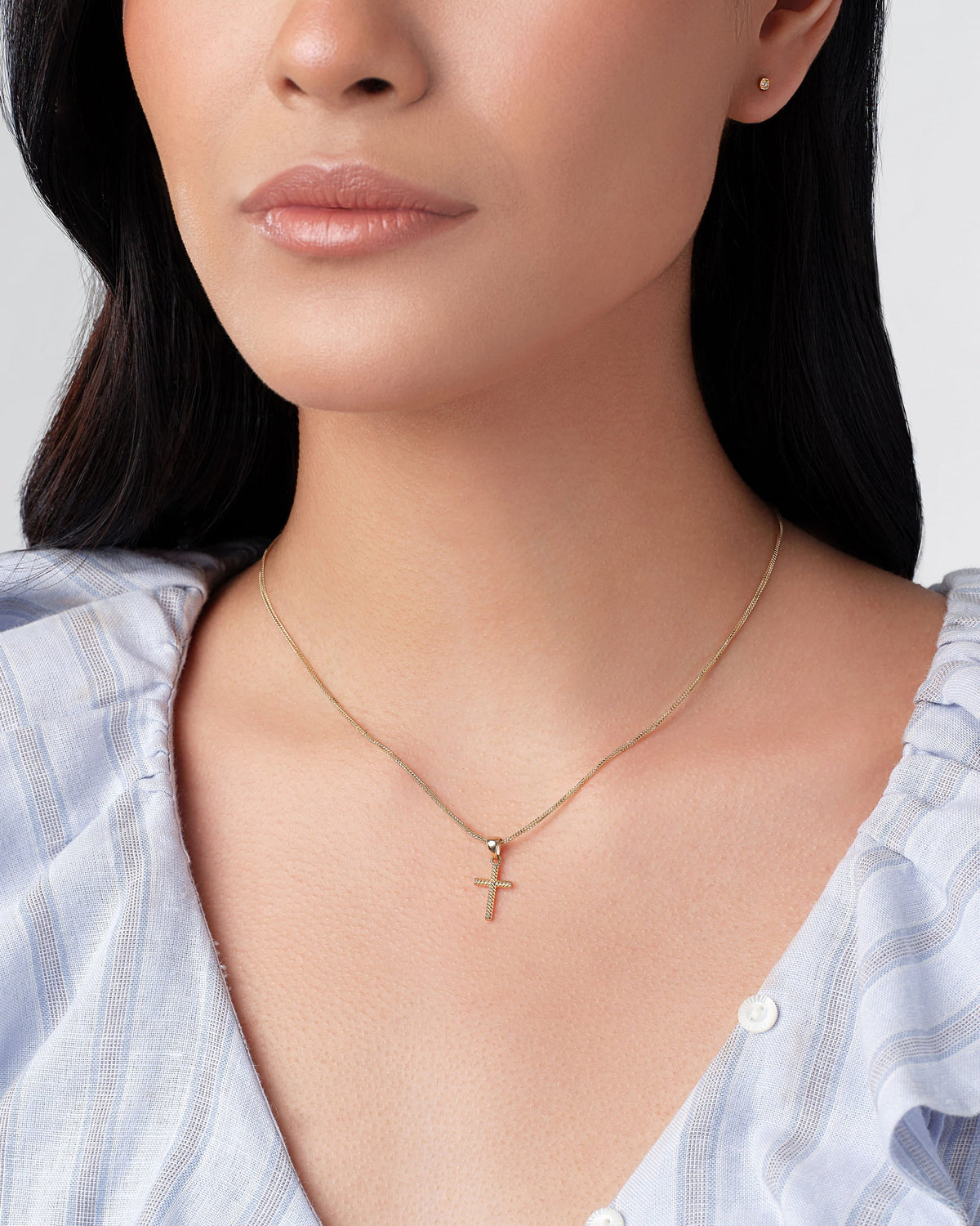 Petite Cross Talisman Charm worn with a striped blouse.