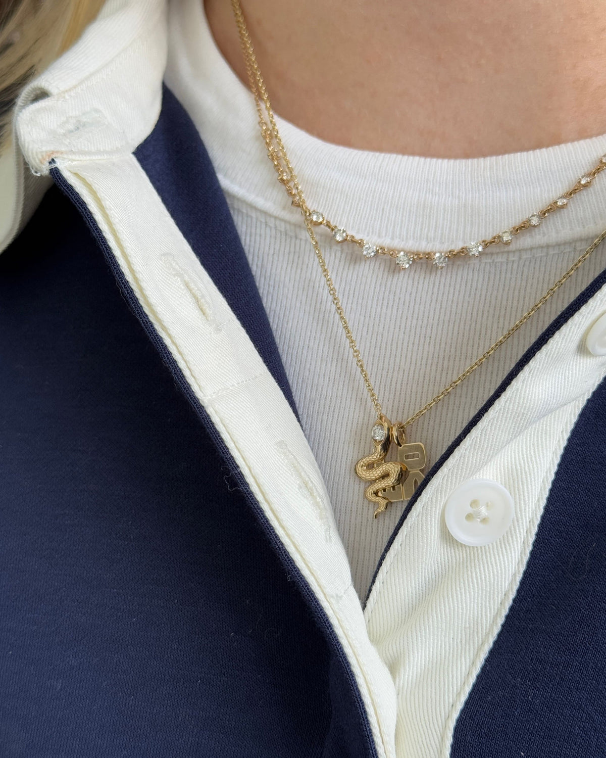 Grande Diamond Cascade Necklace layered with a snake pendant over a white tee and navy jacket.
