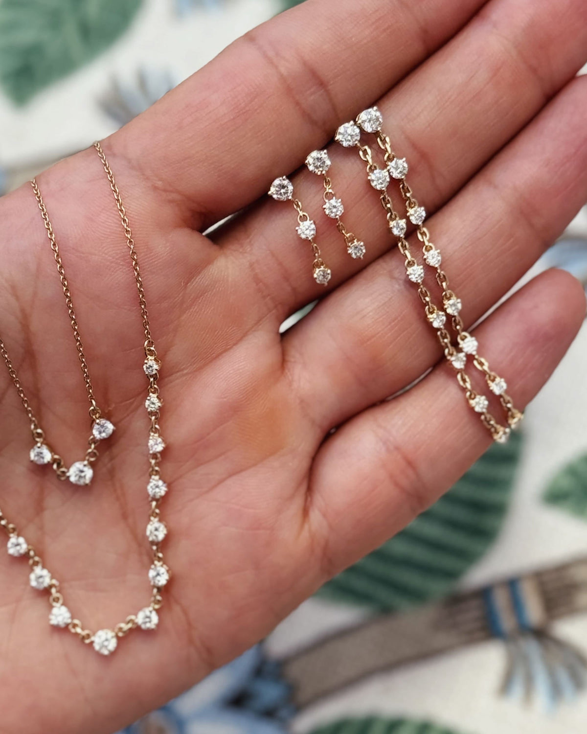 Diamond Cascade necklaces and diamond earrings in an open palm.