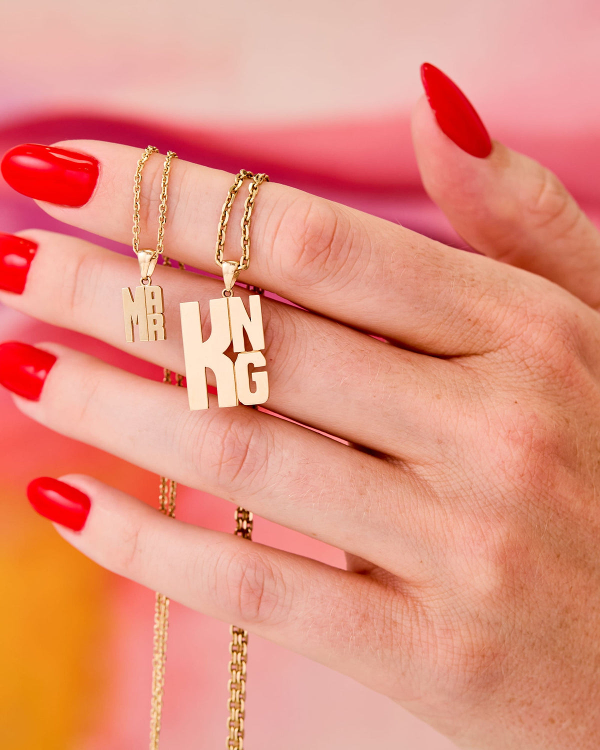 Hand with red nails holding Mini Lucky Strike Monogram Pendants.
