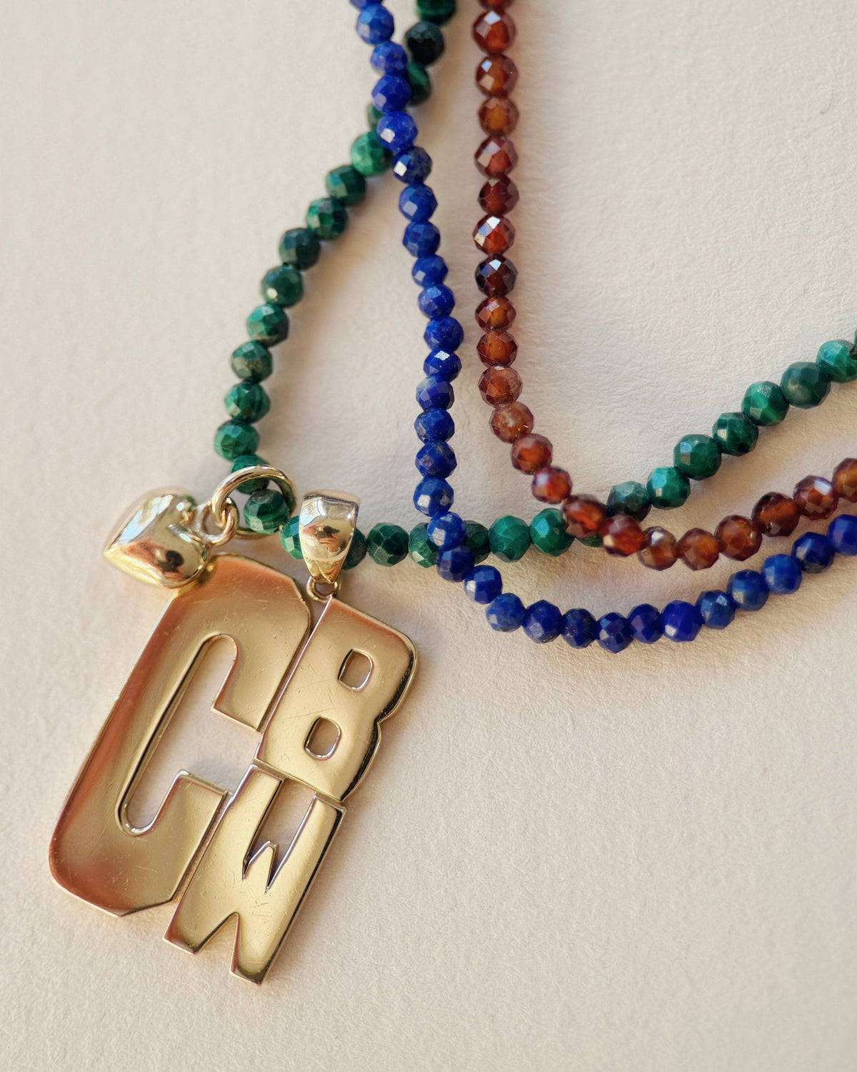 3 beaded necklaces laying down with a large monogram