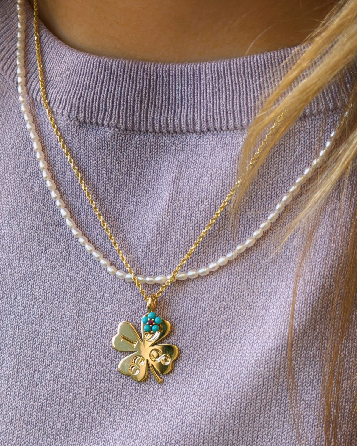 Petite Pearl Beaded Necklace with a clover charm over a lilac sweater.