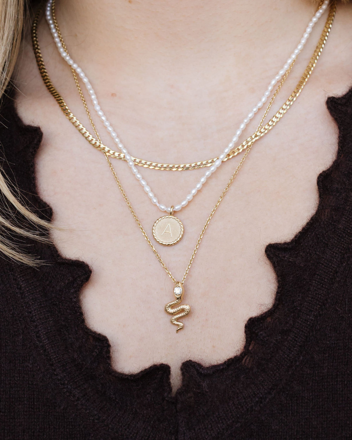 Petite Pearl Beaded Necklace layered with gold chains over a black scalloped top.