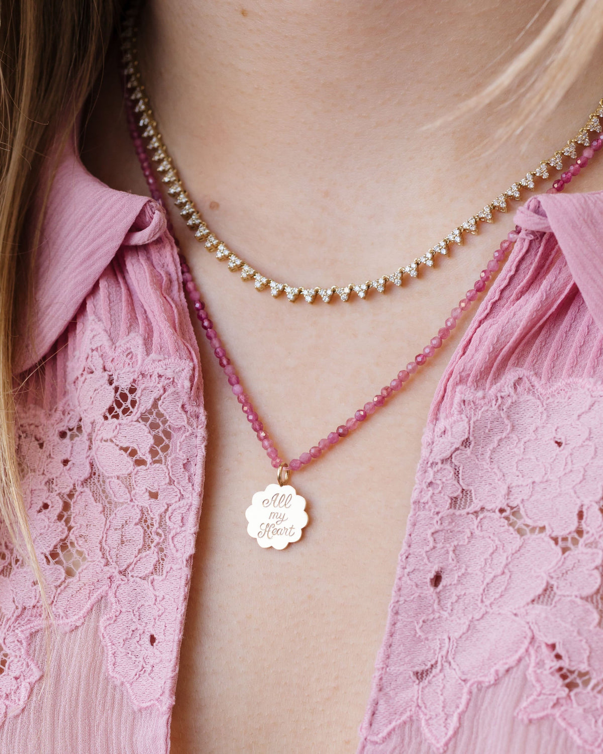 Petite Pink Tourmaline Beaded Necklace with a charm over a pink lace blouse.