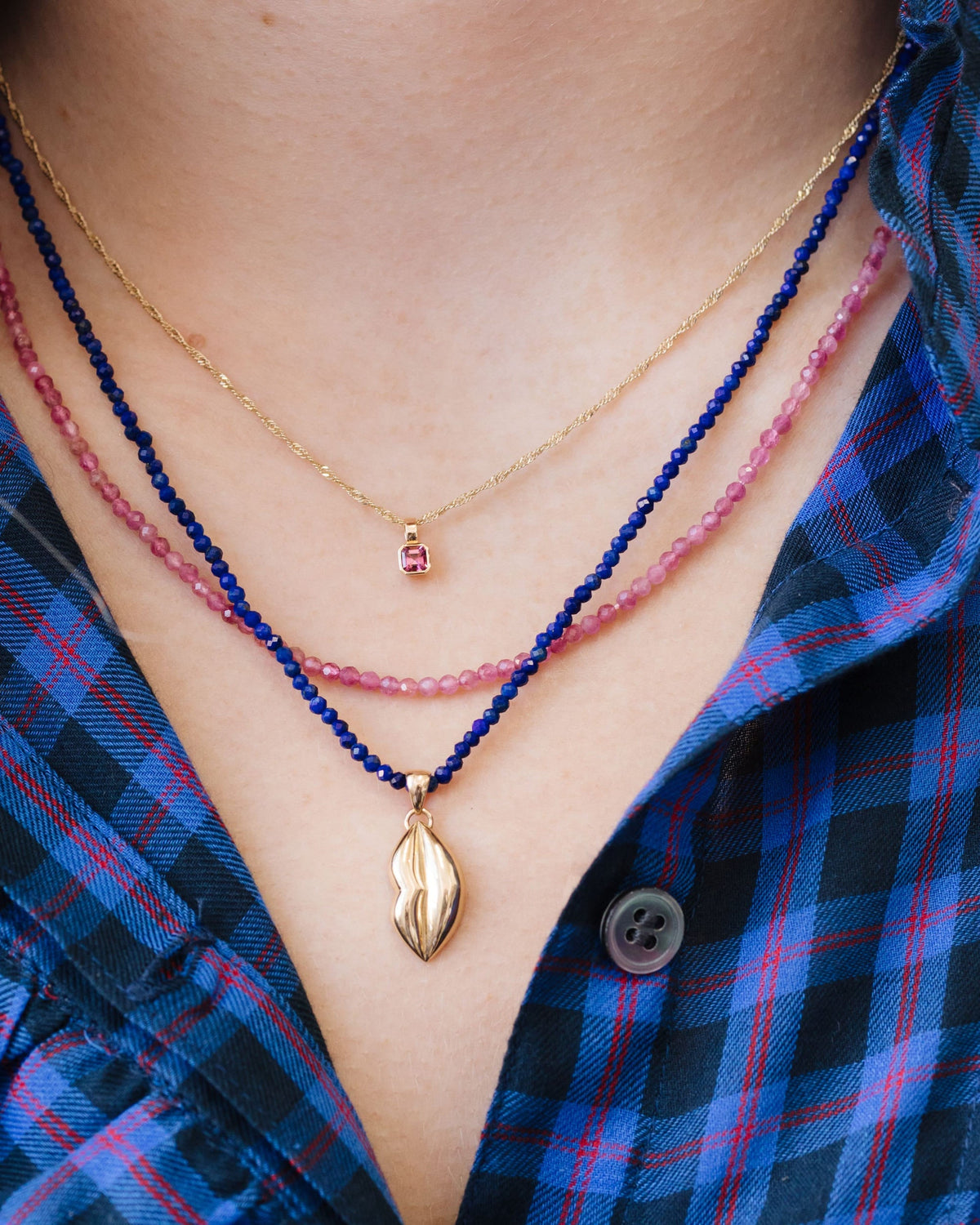Petite Pink Tourmaline Beaded Necklace layered with a lapis strand over a blue gingham top.