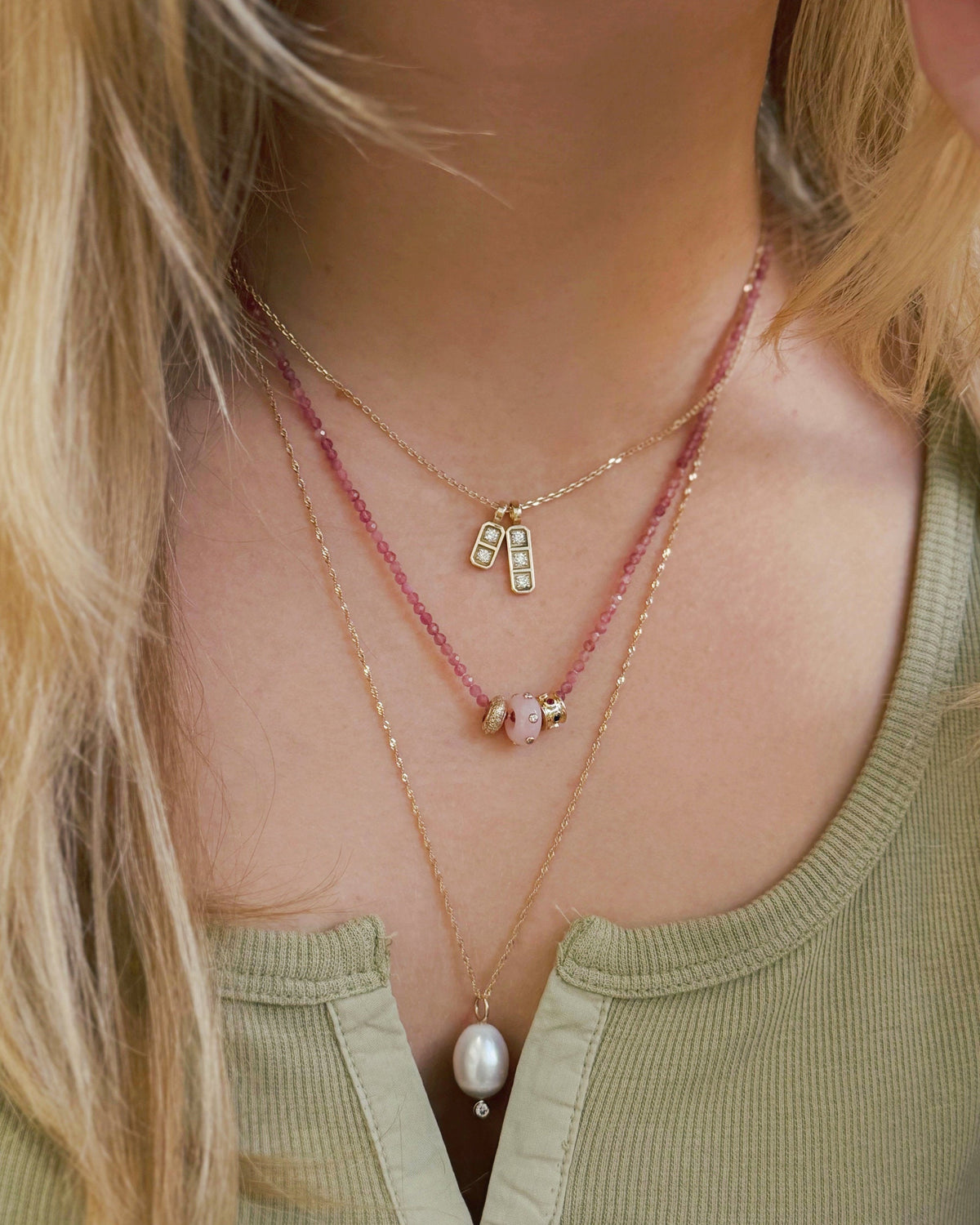 Petite Pink Tourmaline Beaded Necklace with charms and a pearl drop over an olive top.